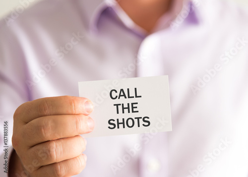 Businessman holding a card with text CALL THE SHOTS