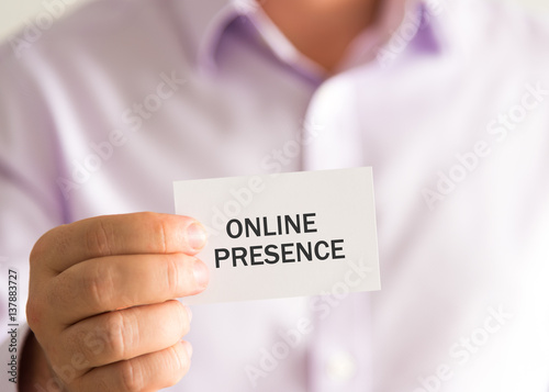 Businessman holding a card with text ONLINE PRESENCE