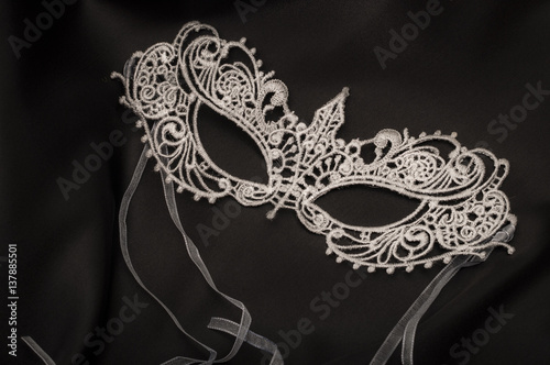 Sexuallity and eroticism concept with a beautiful grey lace masquerade vintage gothic mask on black silk