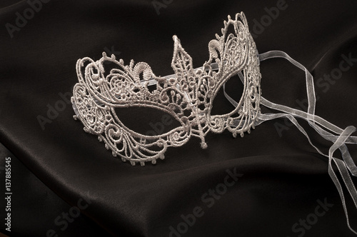 Sexuallity and eroticism concept with a beautiful grey lace masquerade vintage gothic mask on black silk