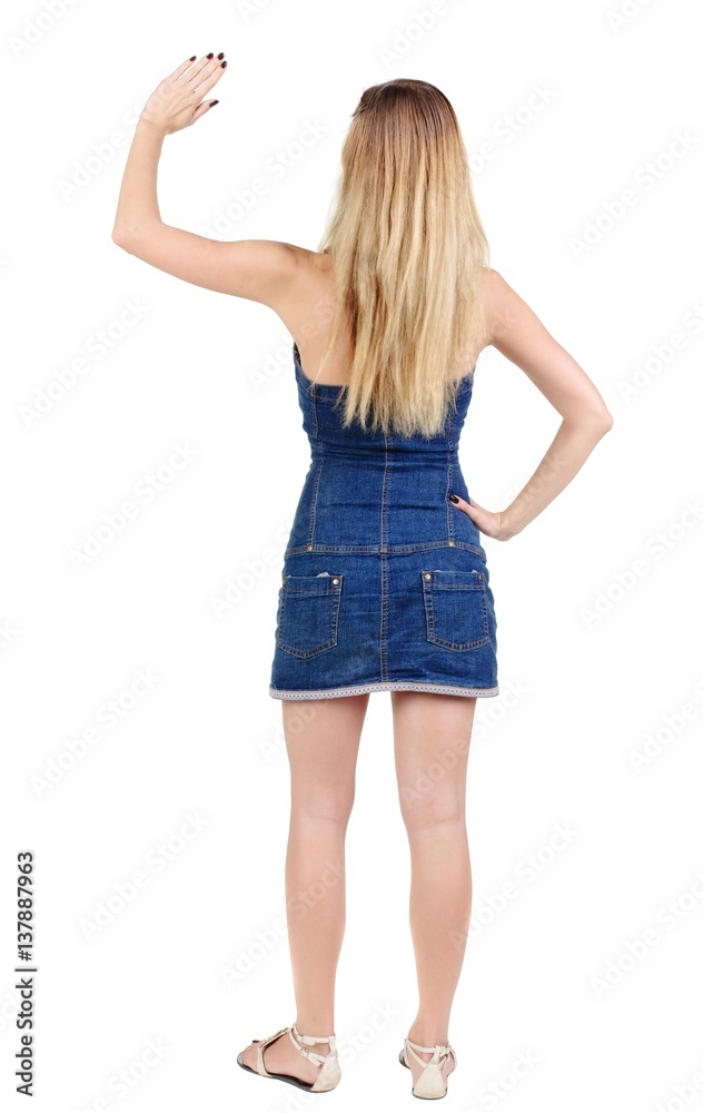 back of view beautiful young woman in jeans dress pointing at wall. rear view. Isolated over white . back of view beautiful young woman in jeans dress pointing at wall. rear view. Isolated over white .
