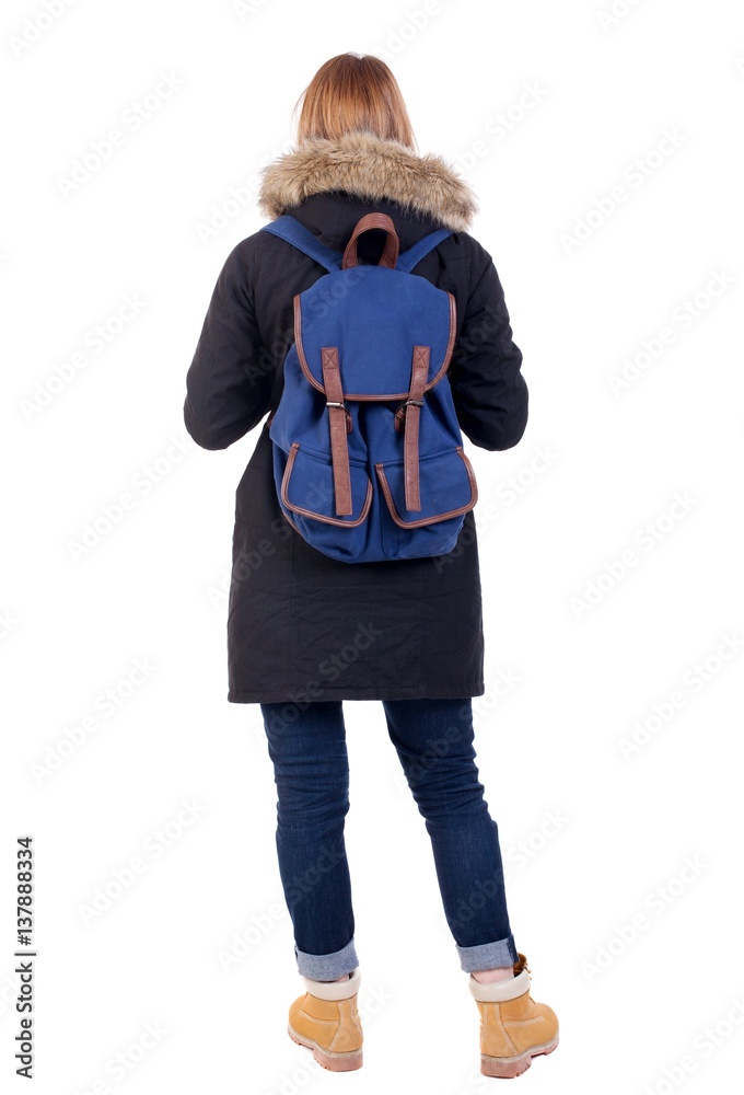 Back view woman in winter jacket  with a backpack looking up