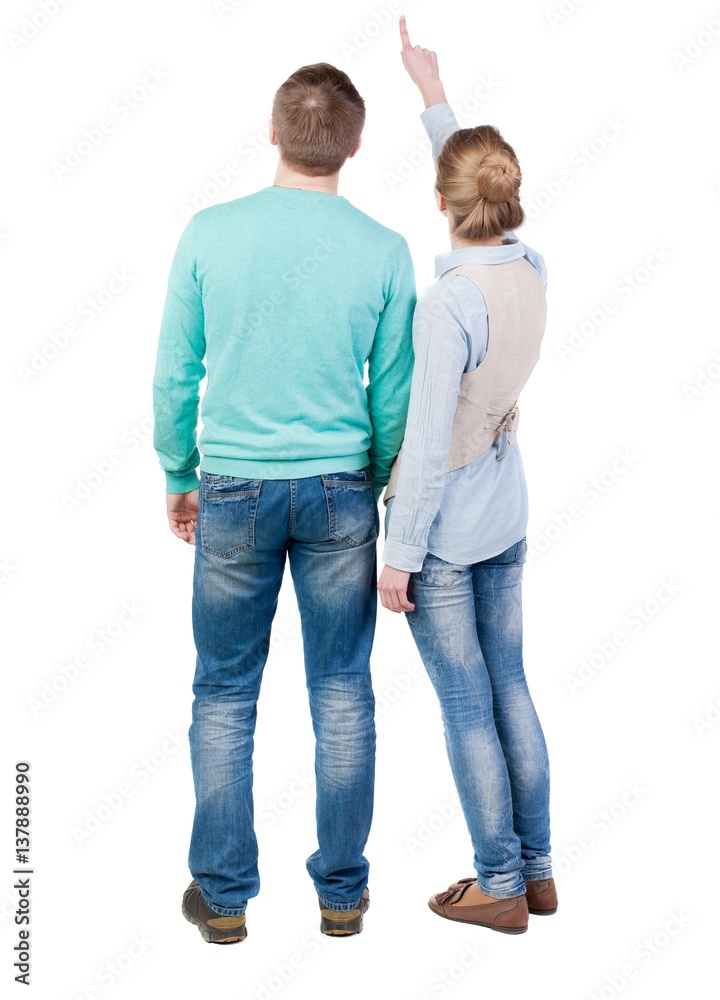 young couple pointing at wal Back view  (woman and man).