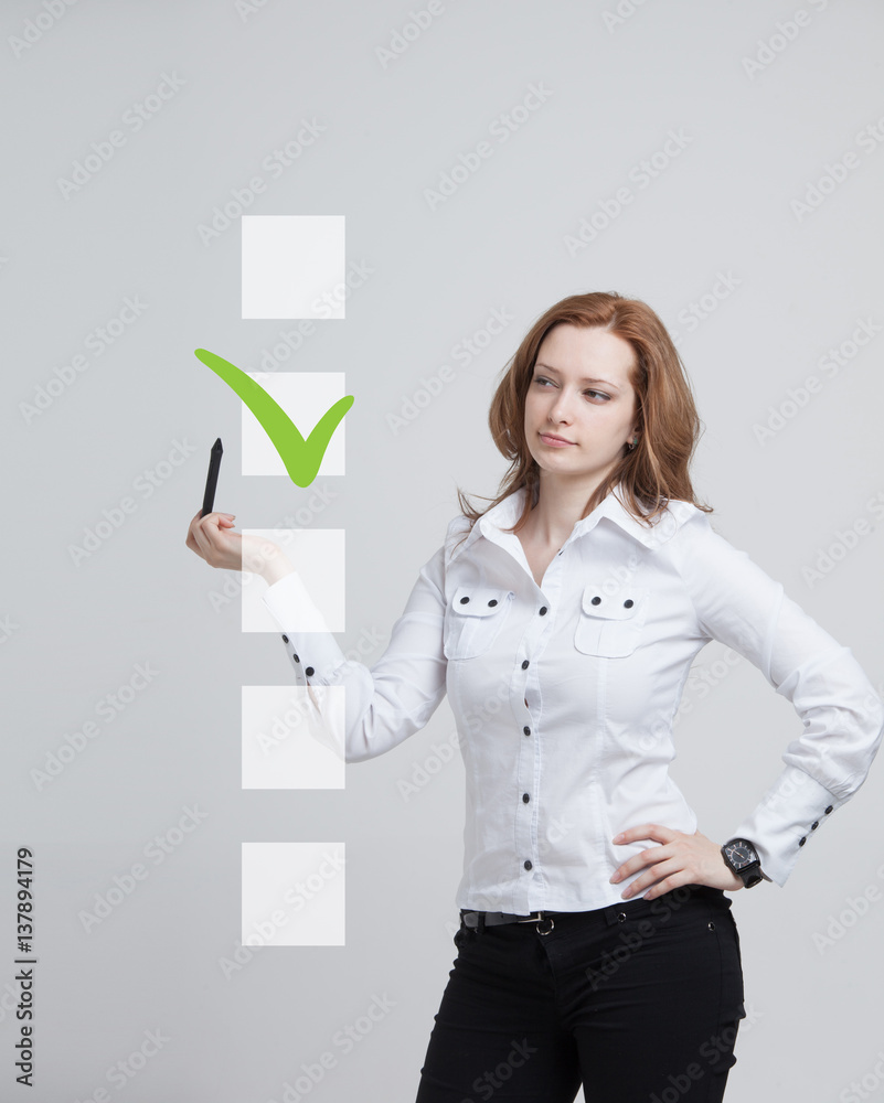 Young business woman checking on checklist box. Gray background. Young business woman checking on checklist box. Gray background.