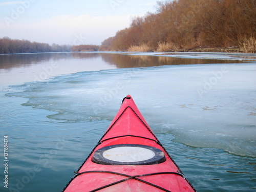 View from the red kayak on the shore with trees in winter the Danube River. Winter kayaking. The nose is bright red kayak.