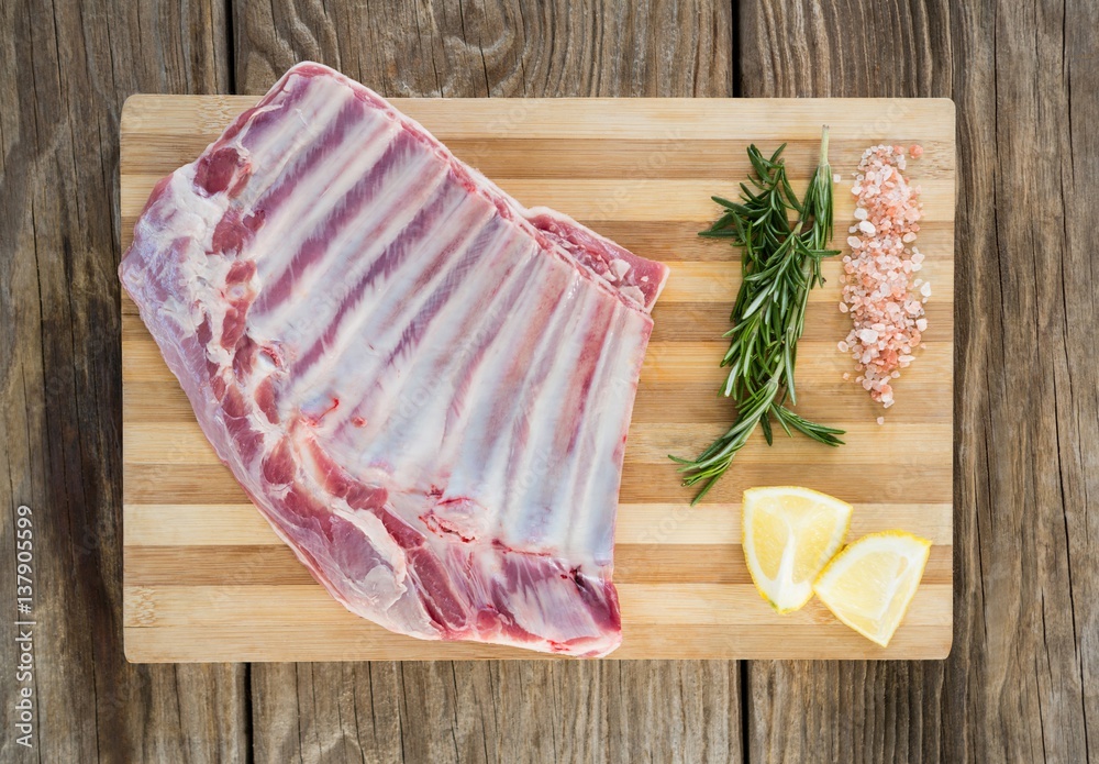 Beef ribs, rosemary herb, salt and lemon on wooden board Beef ribs, rosemary herb, salt and lemon on wooden board