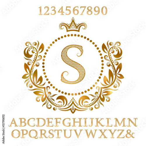 Golden patterned letters and numbers with initial monogram in coat of arms form. Shining font and elements kit for logo design.