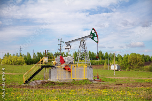 Pump jack with a green field in background