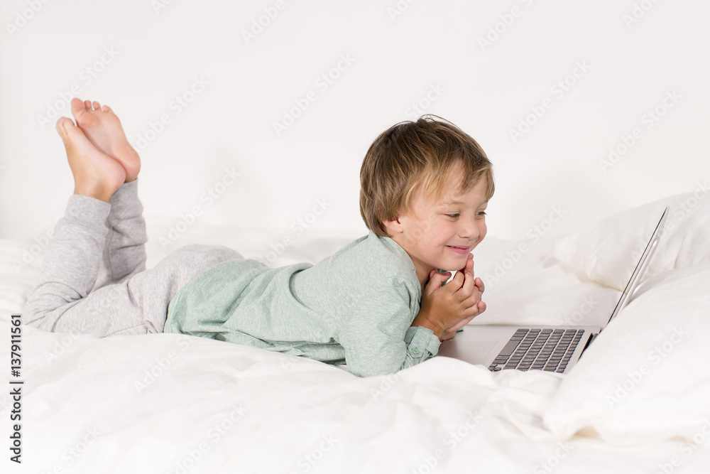Ein Junge mit Notebook liegt auf einem Bett Ein Junge mit Notebook liegt auf einem Bett