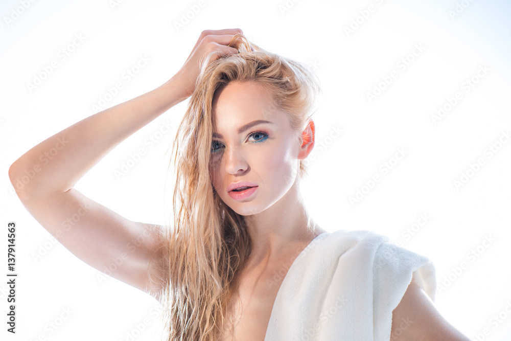 portrait of woman with towel and hand on head looking to camera on white portrait of woman with towel and hand on head looking to camera on white