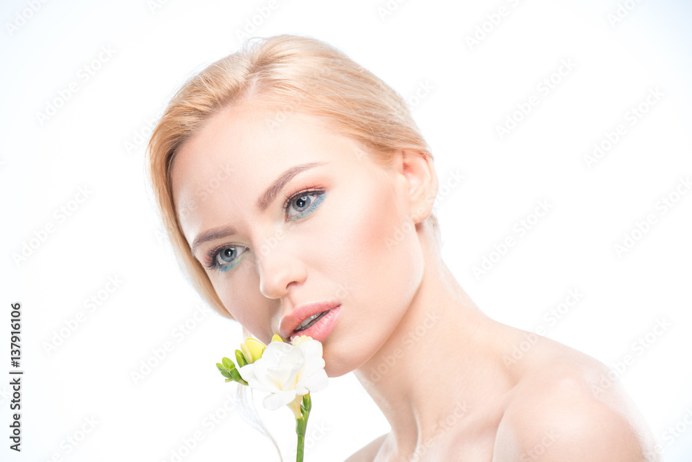 Beautiful young blonde woman holding tender white flower near face, skincare concept Beautiful young blonde woman holding tender white flower near face, skincare concept