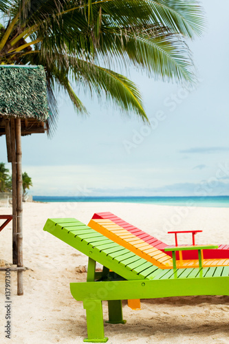 transats colorés sur une belle plage sous un cocotier