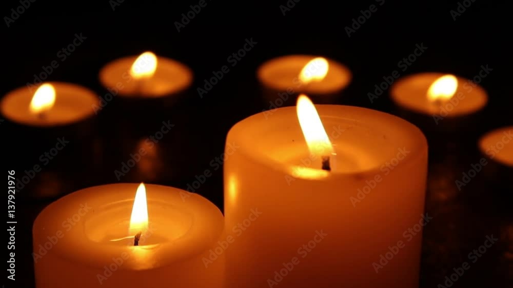 Candles burning at night on a wooden table. Small and big candles and bokeh lights background. Candles burning at night on a wooden table. Small and big candles and bokeh lights background.