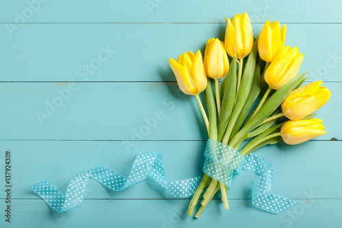 Yellow tulips on blue wooden background