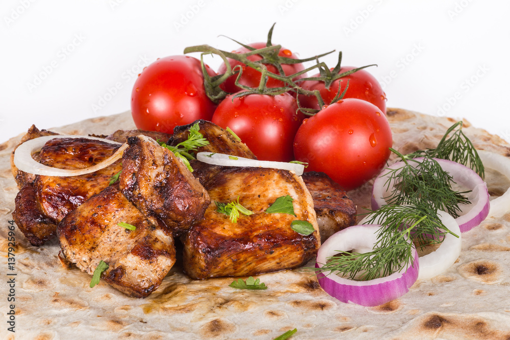 Pieces of roasted meat with vegetables. Grilled meat with tomatoes and greens on a pita