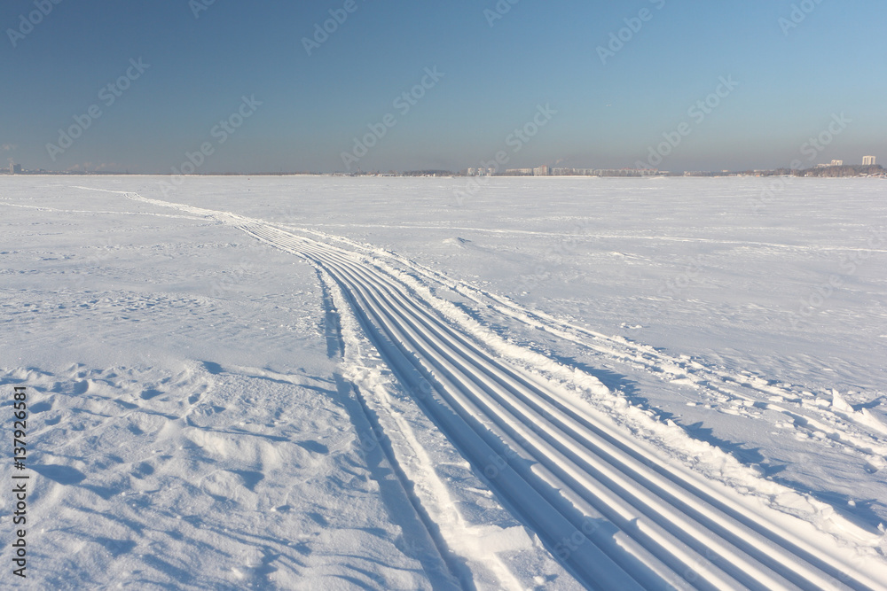 Trace of a snowmobile and sled on a snowy surface of frozen reservoir, Siberia,  Ob River