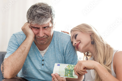 Sad husband give 100 euros to golddigger young wife photo