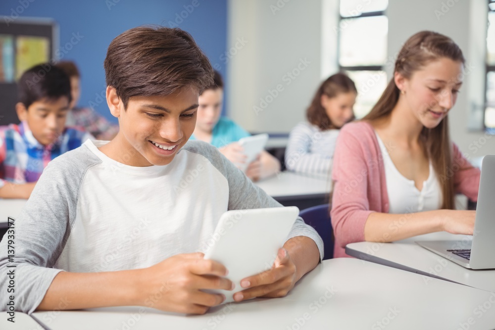 Students using digital tablet and laptop in classroom Students using digital tablet and laptop in classroom