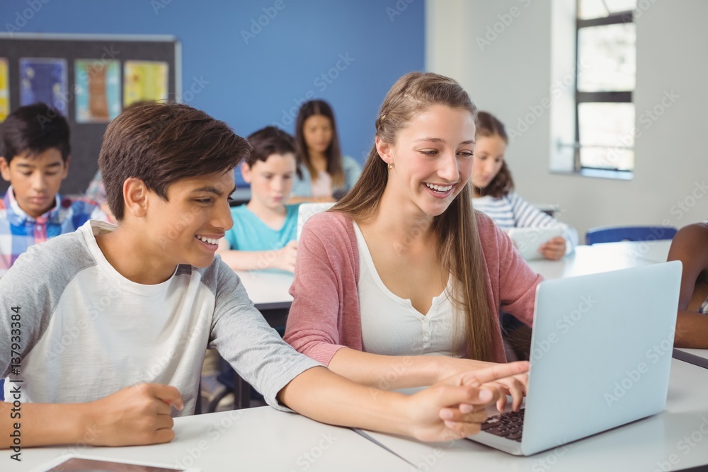 Students using digital tablet and laptop in classroom Students using digital tablet and laptop in classroom