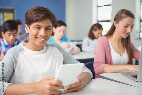 Students using digital tablet and laptop in classroom