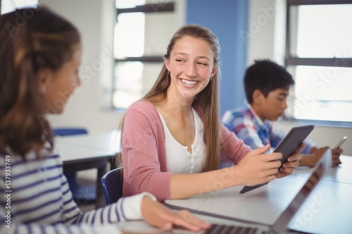 Students using digital tablet and laptop in classroom