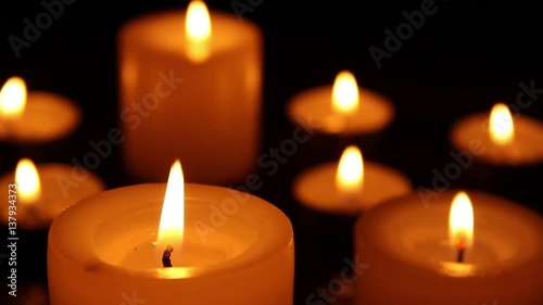 Candles burning at night on a wooden table. Small and big candles and bokeh lights background. 