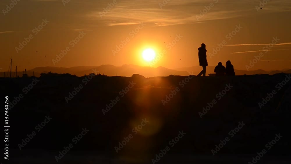 Silhouette of people watching an amazing orange sunset Silhouette of people watching an amazing orange sunset