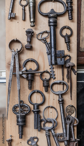 various old keys hanging on a wooden wall