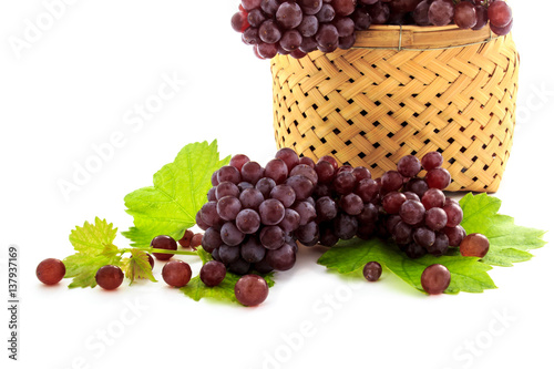 Ripe fresh Organic Table grapes, Champagne Grapes with grape leaves in wicker basket isolated on white background. Small fruit, Snacks for Weight Loss and Diet. Selective focus.
