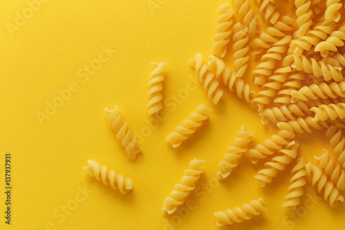 Fusilli pasta spirals on yellow background