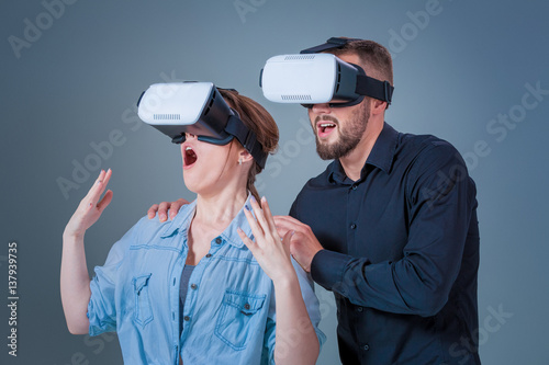 Excited young man and woman having fun with a VR glasses photo