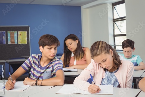 Attentive school kids doing homework in classroom
