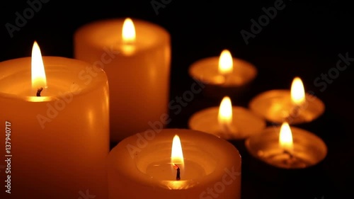 Candles burning at night on a wooden table. Small and big candles and bokeh lights background. 