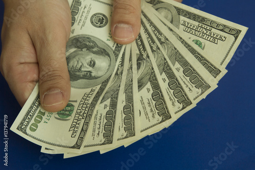 Man's hands holding dollars on dark blue background