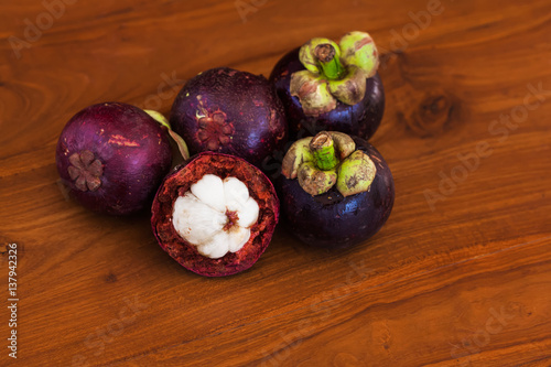 Five fresh mangosteens on wooden brown table