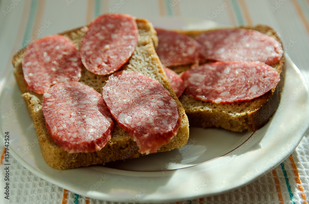 sandwiches of black bread with smoked sausage lies on a plate