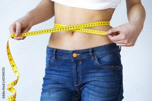 Bild auf Leinwand Young woman with tape measure around waist