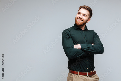 Smiling Bearded man in green shirt with crossed arms