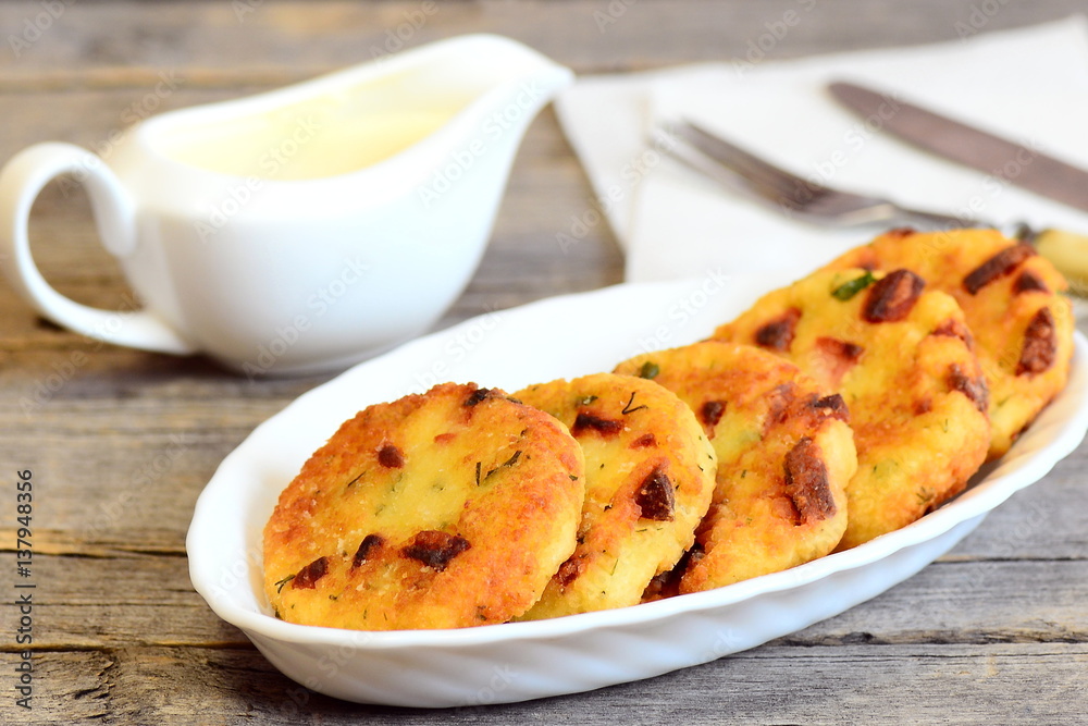 Crispy fried couscous patties with sausage and herbs on a plate, saucer, fork and knife on vintage wooden table. Delicious and quick couscous patties recipe. Closeup