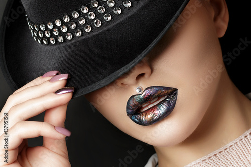 Young woman with fashion make up straightens her hat photo