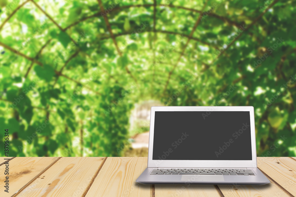 Wood table perspective top on shiny warm light bokeh background with blank laptop Wood table perspective top on shiny warm light bokeh background with blank laptop