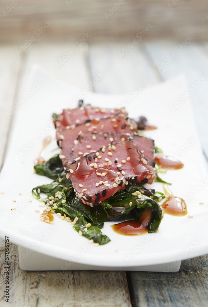 Tuna sashimi with sesame seeds on a bed of spinach Tuna sashimi with sesame seeds on a bed of spinach