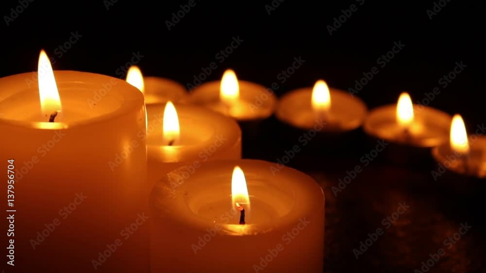 Candles burning at night on a wooden table. Small and big candles and bokeh lights background. Candles burning at night on a wooden table. Small and big candles and bokeh lights background.