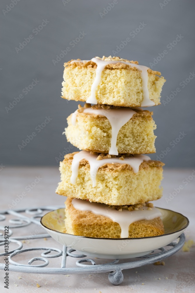 A stack of vanilla cake slices with icing and hazelnuts A stack of vanilla cake slices with icing and hazelnuts