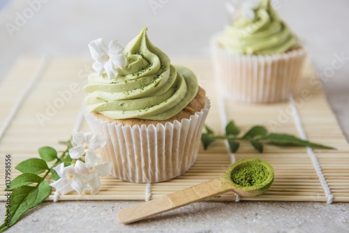 Matcha cupcakes with jasmine flowers and matcha powder on a wooden spoon