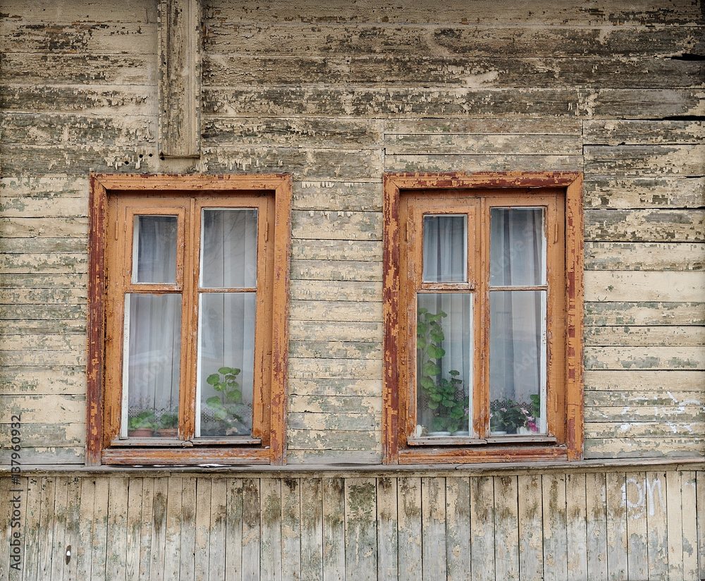 Old wooden house with two windows painted faded white