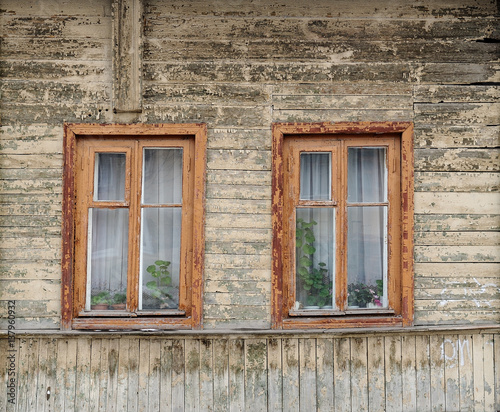 Old wooden house with two windows painted faded white