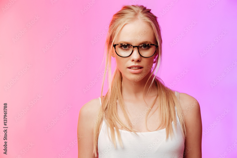 Beautiful woman wearing glasses posing over pink background.