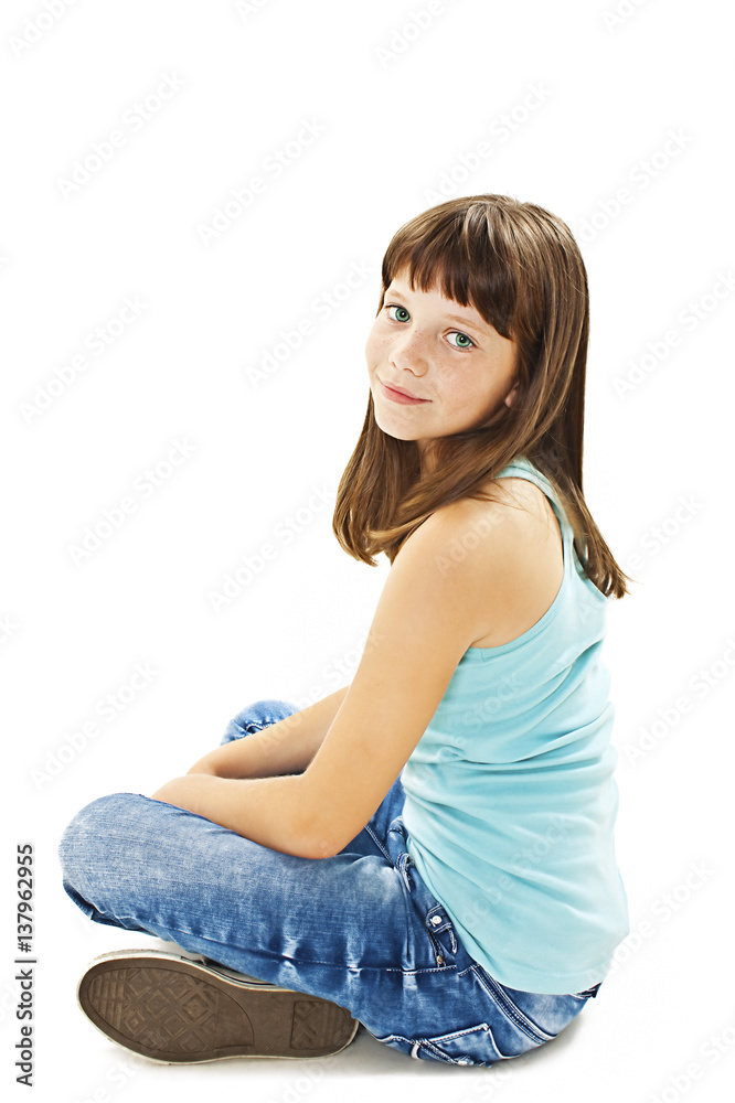 Closeup image of a pretty little girl sitting on the floor in jeans. Isolated on white background Closeup image of a pretty little girl sitting on the floor in jeans. Isolated on white background