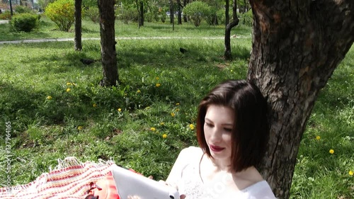 Young lovely girl playing on the tablet in park city, 4K, UHD, UltraHD